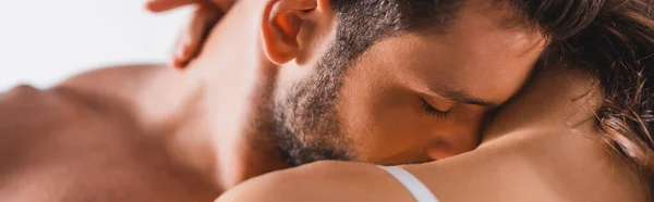 Horizontal crop of shirtless man kissing shoulder of girlfriend on grey background — Stock Photo