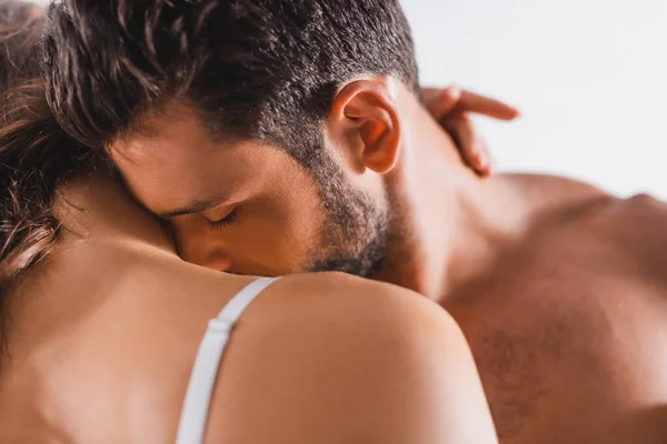 Selective focus of bearded man kissing shoulder of girlfriend on grey background — Stock Photo