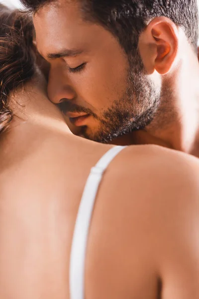 Selective focus of young bearded man kissing neck of girlfriend in bra — Stock Photo