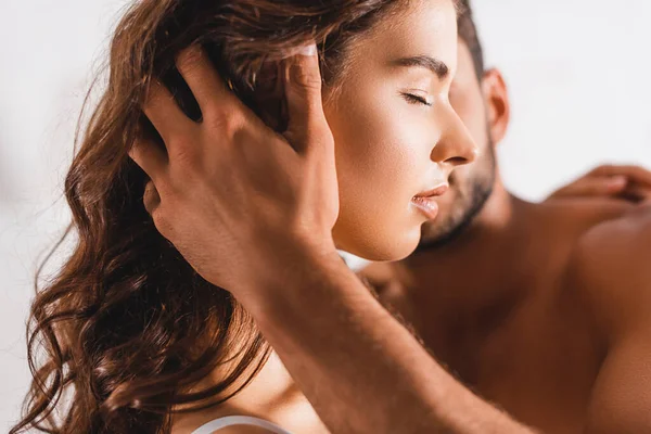 Selective focus of shirtless man touching hair of young woman with closed eye — Stock Photo