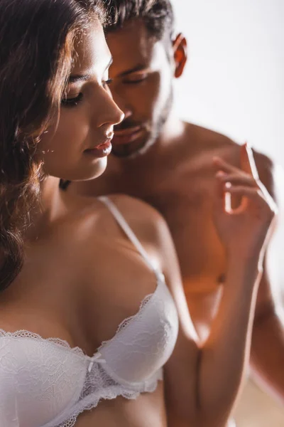 Selective focus of seductive woman in lace bra standing near shirtless man — Stock Photo