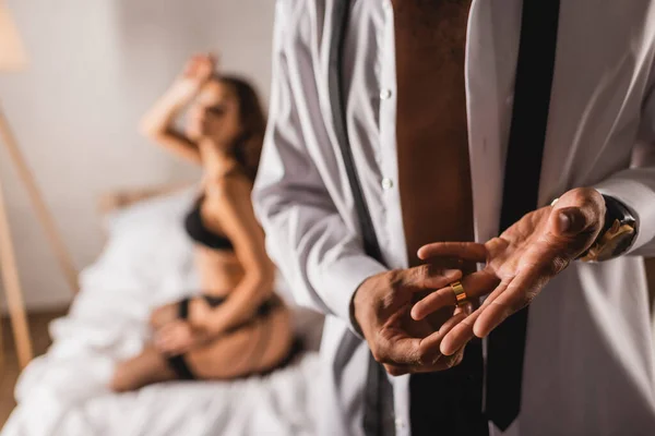 Selektiver Fokus des Mannes, der den Ehering ablegt, während die Frau in Unterwäsche auf dem Bett sitzt — Stockfoto