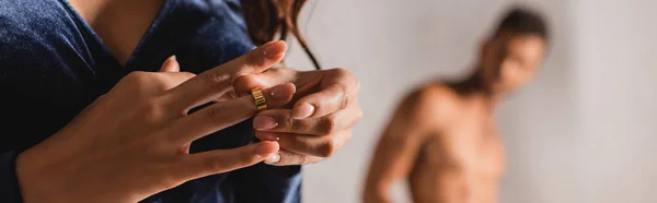 Panoramic orientation of woman taking off wedding ring with shirtless man at background — Stock Photo