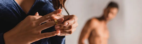 Orientamento panoramico della donna che toglie la fede nuziale con l'uomo senza camicia sullo sfondo — Foto stock