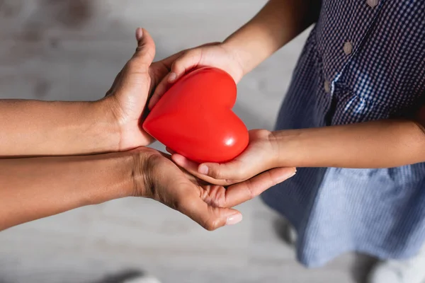 Cropped view of african american mother and child holding red heart model in cupped hands — Stock Photo