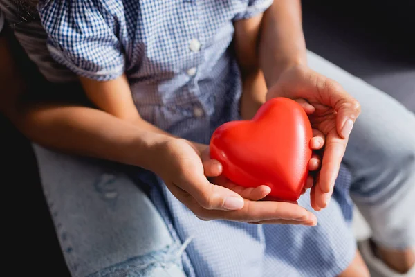 Cropped view of african american mother and daughter holding heart model in cupped hands — Stock Photo
