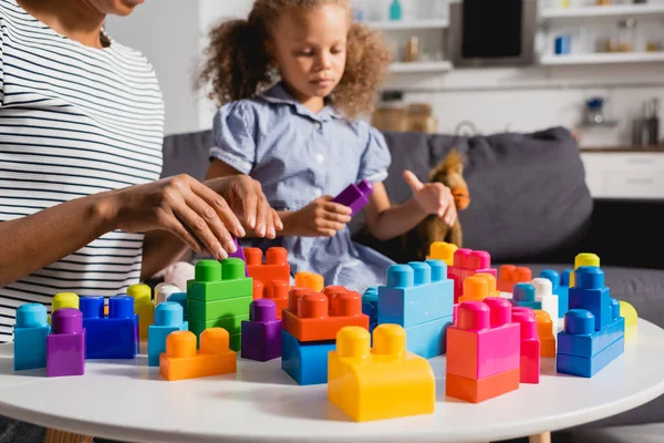 Vista cortada de babá afro-americano e criança brincando com blocos de construção multicoloridos juntos — Fotografia de Stock