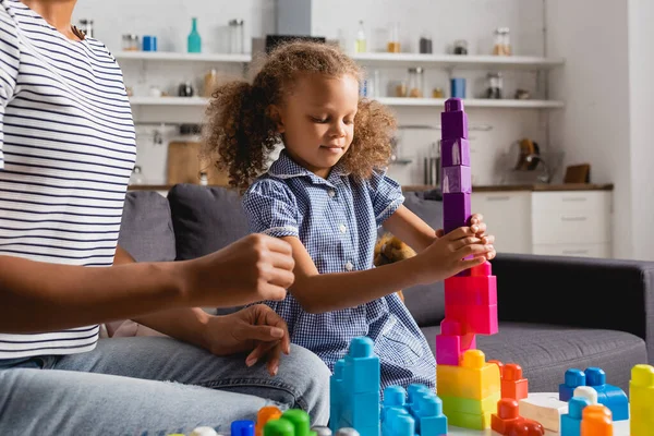 African american child building tower from colorful blocks near nanny — Stock Photo