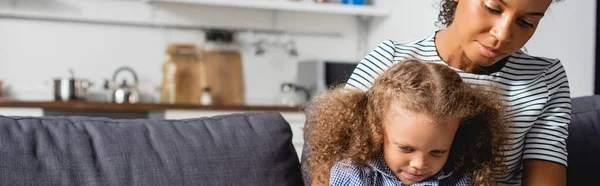 Image horizontale de la mère afro-américaine et sa fille assises ensemble dans la cuisine — Photo de stock