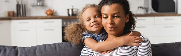 Panoramic concept of african american girl hugging neck of mother in kitchen — Stock Photo