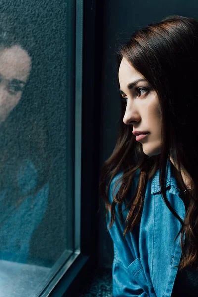 Solitaire et brune femme regardant la fenêtre — Photo de stock