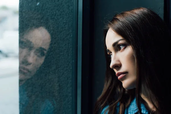 Depressive und brünette Frau blickt auf Fenster — Stockfoto