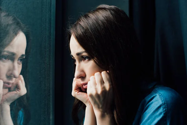 Deprimida morena mulher tocando rosto enquanto olha para a janela — Fotografia de Stock