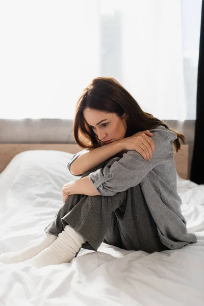 Депрессивная брюнетка женщина, сидящая на кровати дома — стоковое фото