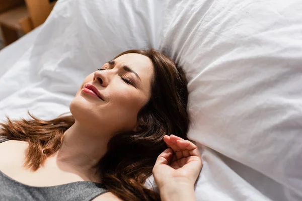 Upset woman with closed eyes lying on bed at home — Stock Photo