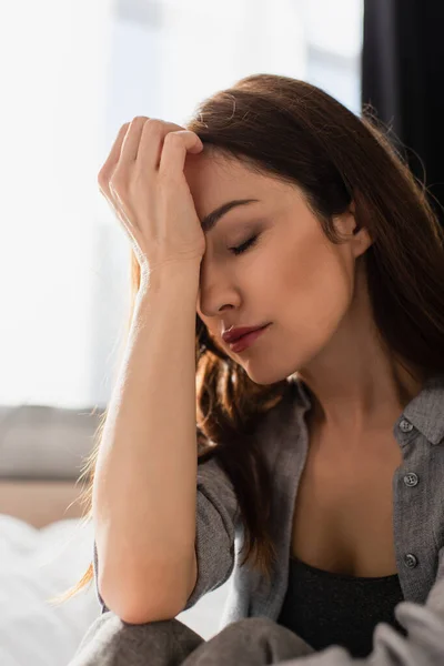 Depressed brunette woman with closed eyes touching face at home — Stock Photo