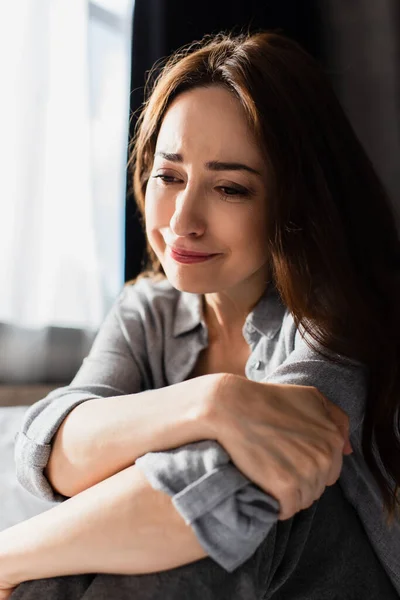 Bouleversé et brunette femme toucher la main tout en étant assis et pleurer à la maison — Photo de stock