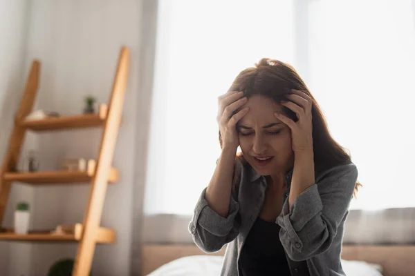 Müde Frau mit geschlossenen Augen, die zu Hause unter Schmerzen und Berührungen am Kopf leidet — Stockfoto