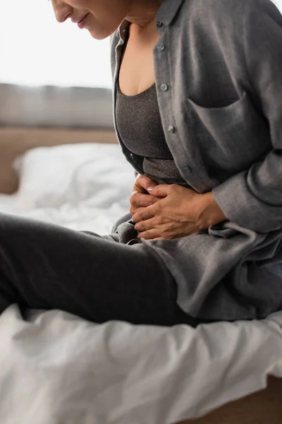 Partial view of woman suffering from stomach ache in bedroom — Stock Photo