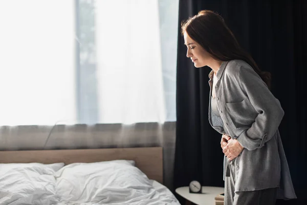 Brunette woman having stomach ache in bedroom — Stock Photo