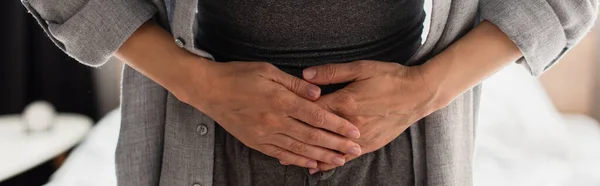 Cosecha horizontal de la mujer que tiene dolor de estómago en casa - foto de stock