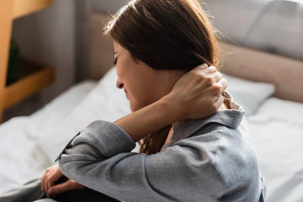 Mécontent femme brune souffrant de douleur au cou dans la chambre — Photo de stock