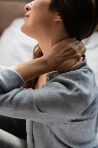 Vue recadrée de la femme brune souffrant de douleurs au cou dans la chambre — Photo de stock