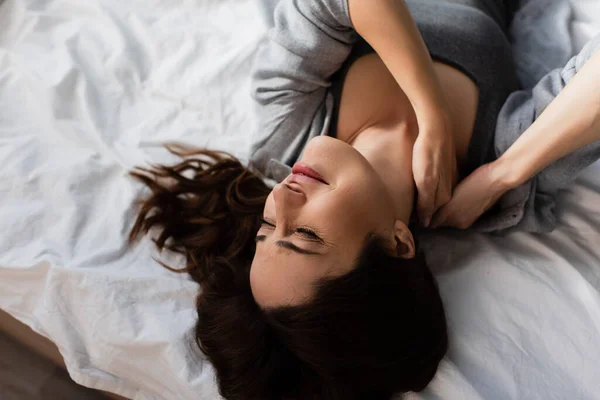 Вид зверху незадоволена брюнетка жінка страждає від болю в шиї в спальні — стокове фото