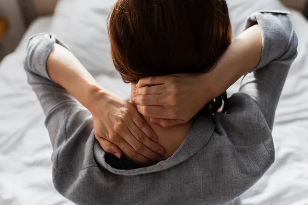 Vista posteriore della donna bruna che ha dolore al collo a casa — Foto stock