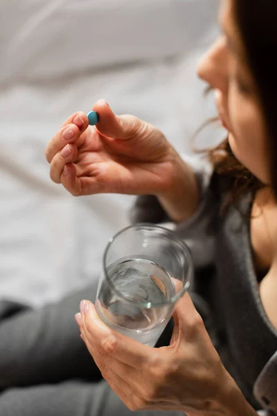 Selective focus of woman holding pill and glass of water at home — Stock Photo