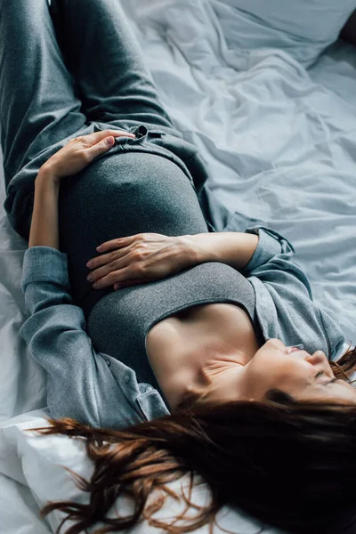 Blick von oben auf Schwangere, die unter Schmerzen im Bett leidet — Stockfoto