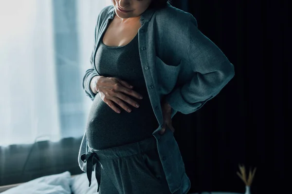 Vue recadrée de la femme enceinte souffrant de douleur et toucher le ventre — Photo de stock