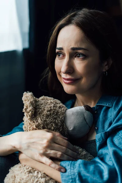 Verärgerte brünette Frau hält Teddybär und schaut weg — Stockfoto