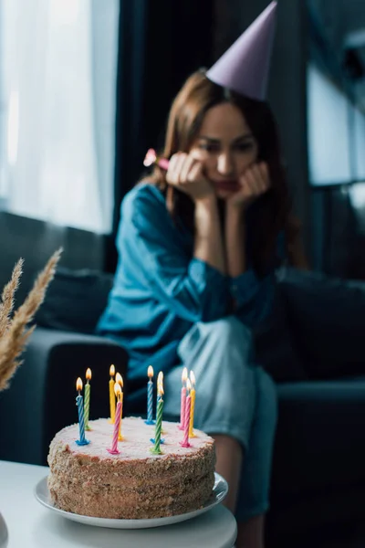 Foco seletivo de bolo de aniversário na mesa de café perto da mulher chateada — Fotografia de Stock