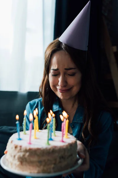 Foco seletivo da mulher chateada chorando enquanto segura bolo de aniversário com velas — Fotografia de Stock