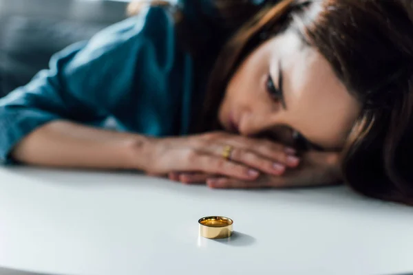 Foyer sélectif de la femme déprimée regardant la table basse avec anneau d'or, concept de divorce — Photo de stock