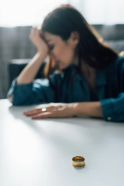Selektiver Fokus des Goldenen Rings auf Couchtisch in der Nähe einer depressiven Frau, Scheidungskonzept — Stockfoto