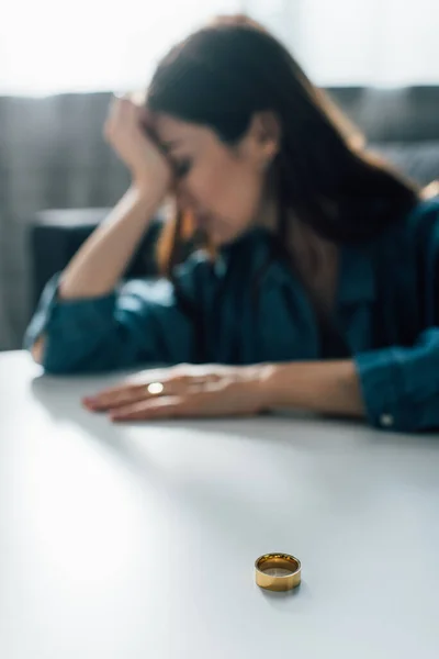 Selective focus of golden ring on coffee table near depressed woman, divorce concept — Stock Photo