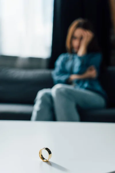 Selective focus of golden ring on coffee table near sad woman, divorce concept — Stock Photo