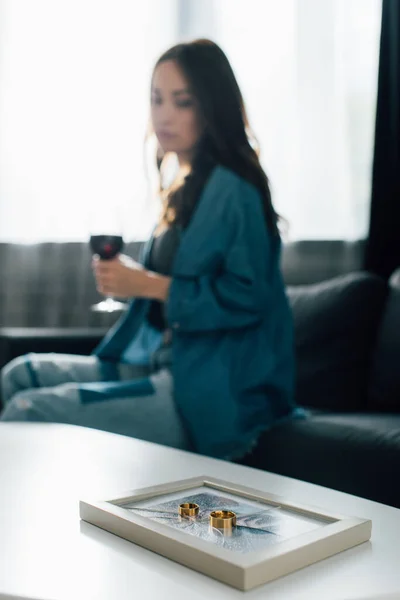Selective focus of golden rings on photo frame with broken glass near brunette woman,  divorce concept — Stock Photo