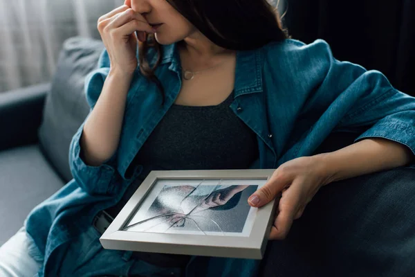 Partial view of upset woman holding photo with broken glass in frame, divorce concept — Stock Photo