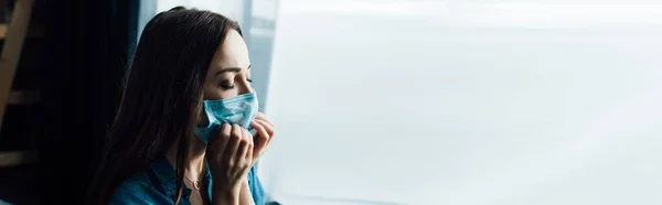 Panoramic shot of brunette woman touching medical mask at home — Stock Photo