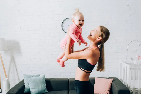 Mulher em sportswear segurando menina na sala de estar — Fotografia de Stock