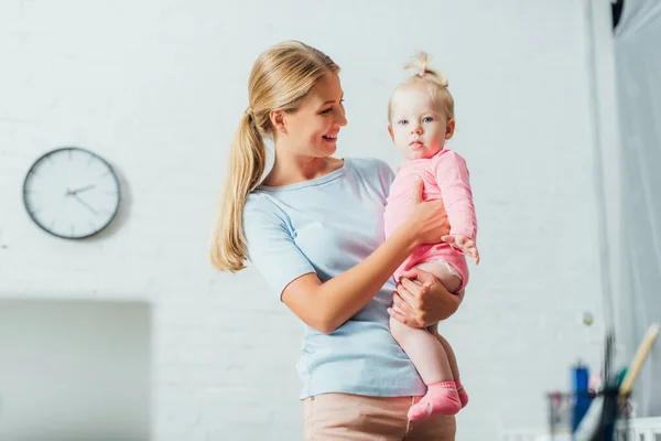 Concentration sélective de la femme tenant bébé fille à la maison — Photo de stock