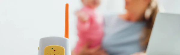 Panoramic shot of baby monitor with mother holding infant at background — Stock Photo