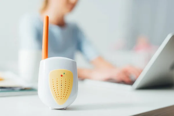 Focus selettivo del baby monitor sul tavolo e sulla donna che utilizzano il computer portatile a casa — Foto stock