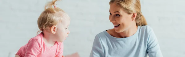 Cultivo panorámico de la mujer mirando a la hija bebé en casa - foto de stock