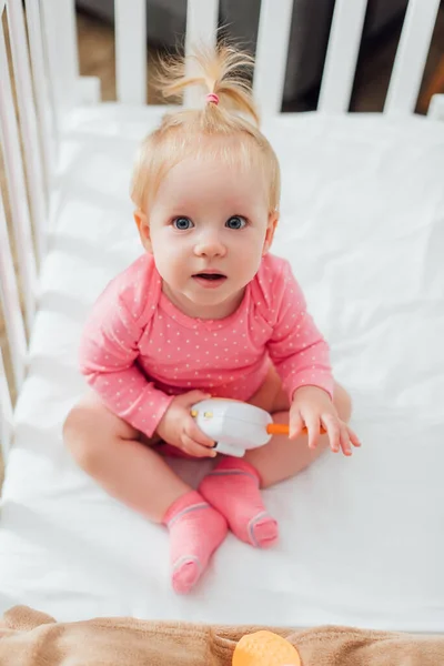 Vue aérienne du bébé fille tenant le moniteur de bébé dans le berceau — Photo de stock