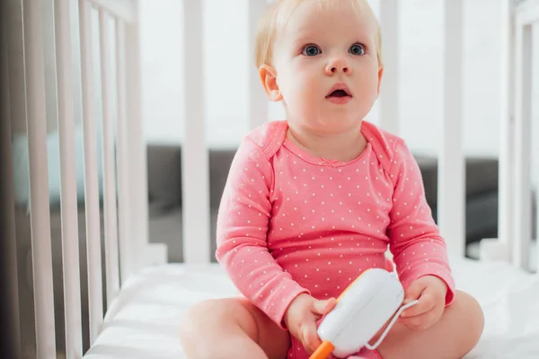 Selective focus of excited infant holding baby monitor in crib — Stock Photo