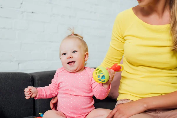 Bambino ragazza holding giocattolo vicino madre su divano a casa — Foto stock